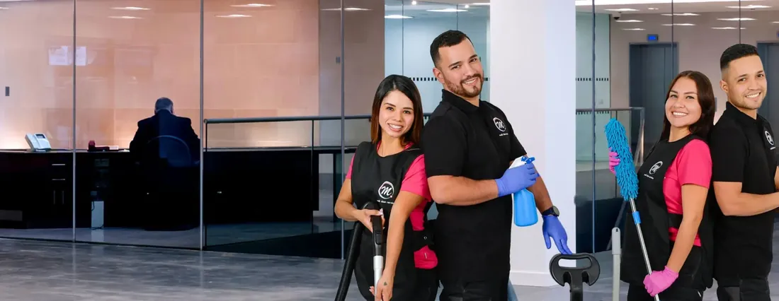 Büroreinigung & Gewerbe: Vier Mitarbeitende von Multi Clean Service mit Staubsauger, Moppwagen und Staubwedel in der verglasten Lobby eines Bürogebäudes